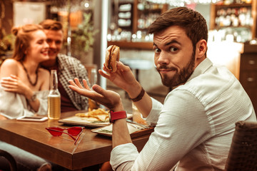 Face portrait of male shrugging shoulders while his friends cuddling