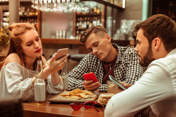 Bored group of three friends being glued to their phones