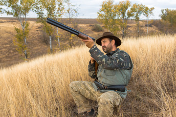 Hunter with a hat and a gun in search of prey in the steppe	