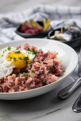 Norddeutscher Hamburger Labskaus mit Rindfleisch Corned Beef, Rote Beete, Kartoffeln, Saure Gurken, Spiegelei und Rollmops auf Teller