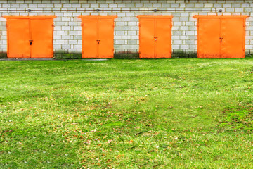 Obraz premium Orange garage door. old and rutic. ugly doors against green loan