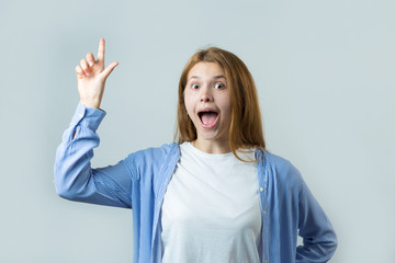 Emotional portrait of a red-haired girl on a gray background, stormy emotions, business concept.