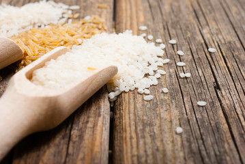 three different types of rice on scoops, old wood table