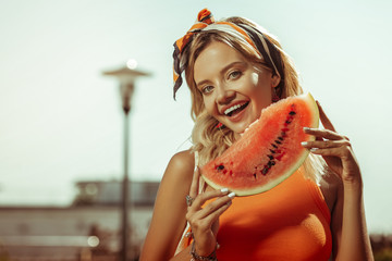 Lovely beaming smiling radiant appealing lady holding a watermelon piece