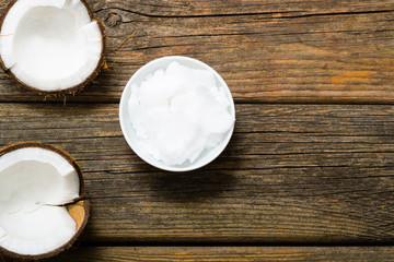 pile of rigid coconut oil on china dish and broken coconut shells, old wood table