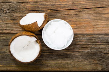 pile of rigid coconut oil on china dish and broken coconut shells, old wood table