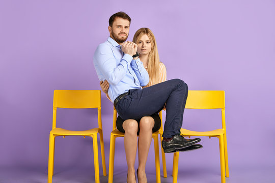 Friendly male and female students having fun and playing fool. Young man sitting on woman's lap, looking in camera and waiting for job interview - Powered by Adobe
