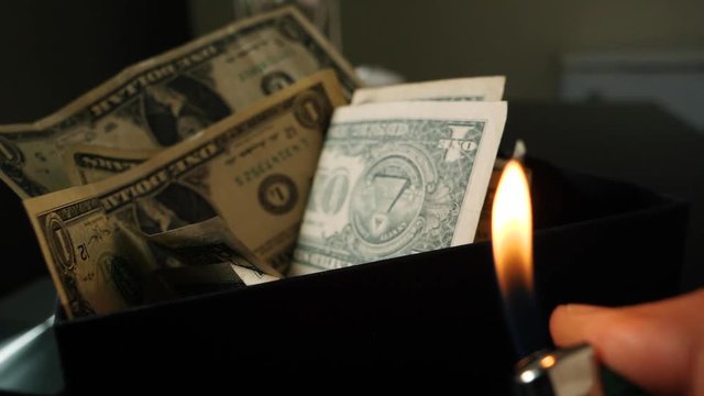 A cigarette lighter emits a flame with dollar bills in a box, money background. Dollars money set With Shallow Dof. Dollars, money close up.