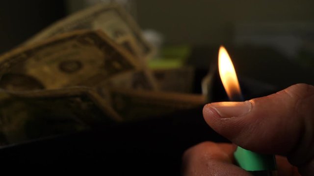 A cigarette lighter emits a flame with dollar bills in a box, money background. Dollars money set With Shallow Dof. Dollars, money close up.