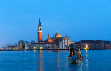 Venetian gondolier punting gondola through green canal waters of Venice Italy © muratart