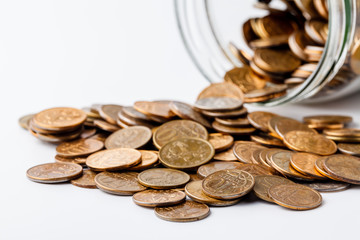 Coins placed on glass jar and coins scattered around the glass jar