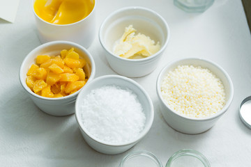 beeswax, emulsan, shea butter, cosmetic lotion cream diy do it yourself ingredients on white textile