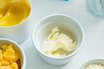 beeswax, emulsan, shea butter, cosmetic lotion cream diy do it yourself ingredients on white textile