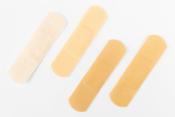 Adhesive plasters of various skin tones from light beige to saturated. A set of adhesive plasters on a white background. Necessary items for summer activities, treatment of wounds, scratches.