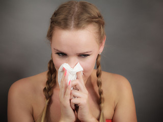 Woman being sick having flu sneeze into tissue