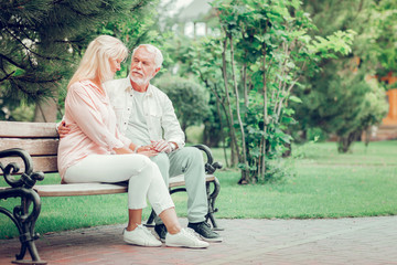 Positive aged couple resting on the bench