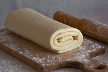 Rolled raw homemade puff pastry on kitchen board 