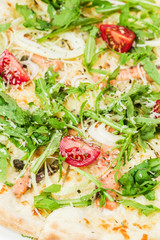 Homemade italian pizza, fresh cherry tomatoes and basil, arugula served on wooden board