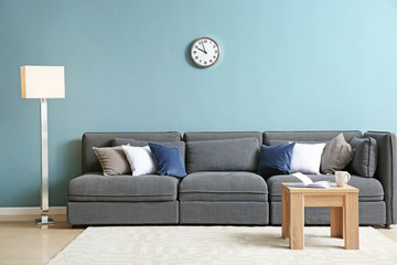 Comfortable sofa and table near color wall