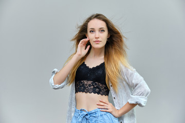 Photograph of a portrait of a beautiful girl woman with long dark flowing hair, satisfied life on a gray background. She stands in front of the camera in different poses with different emotions.