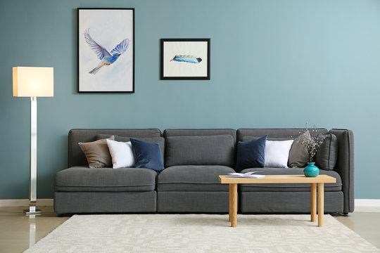 Comfortable sofa and table near color wall