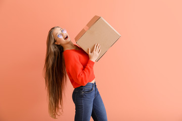 Young woman with cardboard box on color background