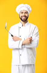 Handsome male chef on color background