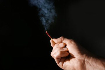 Male hand with match on dark background