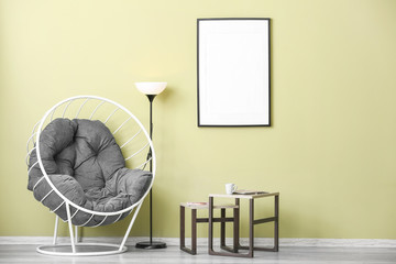 Comfortable armchair and tables near color wall