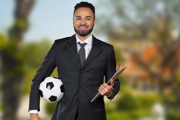 African businessman holding a soccer ball. Soccer trainer