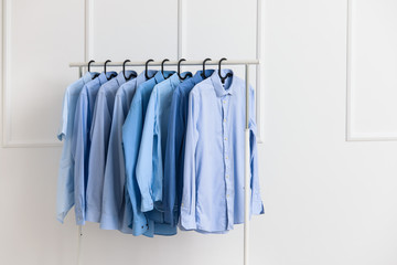 Rack with clothes after dry-cleaning near white wall