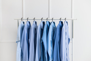 Rack with clothes after dry-cleaning near white wall