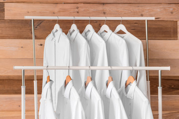 Racks with clothes after dry-cleaning on wooden background