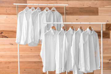 Racks with clothes after dry-cleaning on wooden background