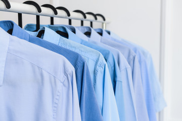 Rack with clothes after dry-cleaning near white wall, closeup