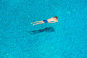 Side view of young man sleeping peacefully on lifebuoy in swimming pool. He is relaxing on vacation.