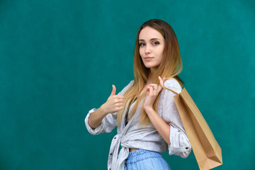 Photograph of a portrait of a beautiful girl woman with long dark flowing hair, loves shopping, on a green background with packages from the store. She is standing in different poses and smiling.