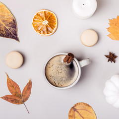 Coffee with cinnamon and autumn leaves on gray background. Autumn creative composition