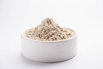 bajra  atta / flour of pearl millet served in a bowl with small wooden scoop, selective focus
