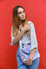 Photograph of a portrait of a beautiful fashionable beauty woman girl with long dark flowing hair, on a red background with a bag. She is standing in different poses and smiling.