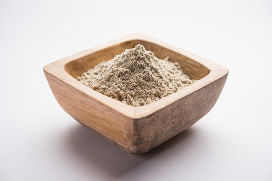 bajra  atta / flour of pearl millet served in a bowl with small wooden scoop, selective focus