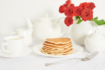 Independence Day on July 4th, American pancakes on the table next to the crockery and red roses.