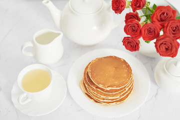 Fototapeta na wymiar Independence Day on July 4th, American pancakes on the table next to the crockery and red roses.