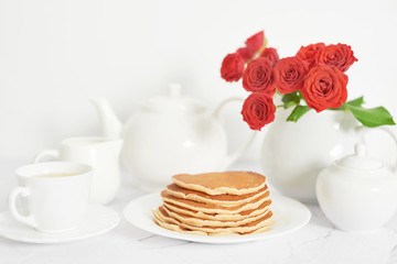 Independence Day on July 4th, American pancakes on the table next to the crockery and red roses.