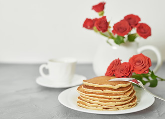 Independence Day on July 4th, American pancakes on the table next to the crockery and red roses.