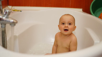 Funny little child playing with water in a bathroom. Toddlers bathes.