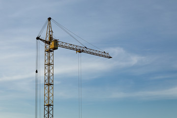 Industrial construction building crane against blue cloudy sky
