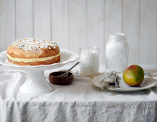 White cake with cream and white wood background
