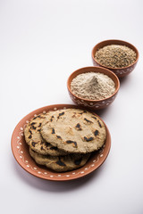 Bajra (pearl millet) / sorghum grains with it's flour or powder in a bowl, selective focus