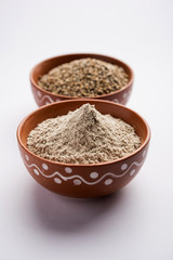 Bajra (pearl millet) / sorghum grains with it's flour or powder in a bowl, selective focus